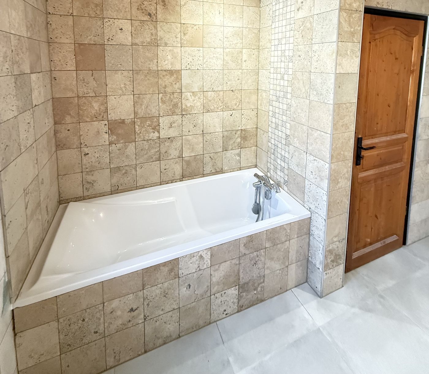 Salle de bain en carrelage effet pierre avec baignoire habillée